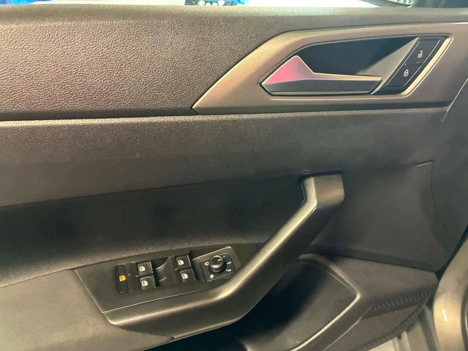 Vue rapprochée de la porte intérieure côté conducteur d'une Volkswagen Polo 2018, avec commandes de vitres et verrouillage.