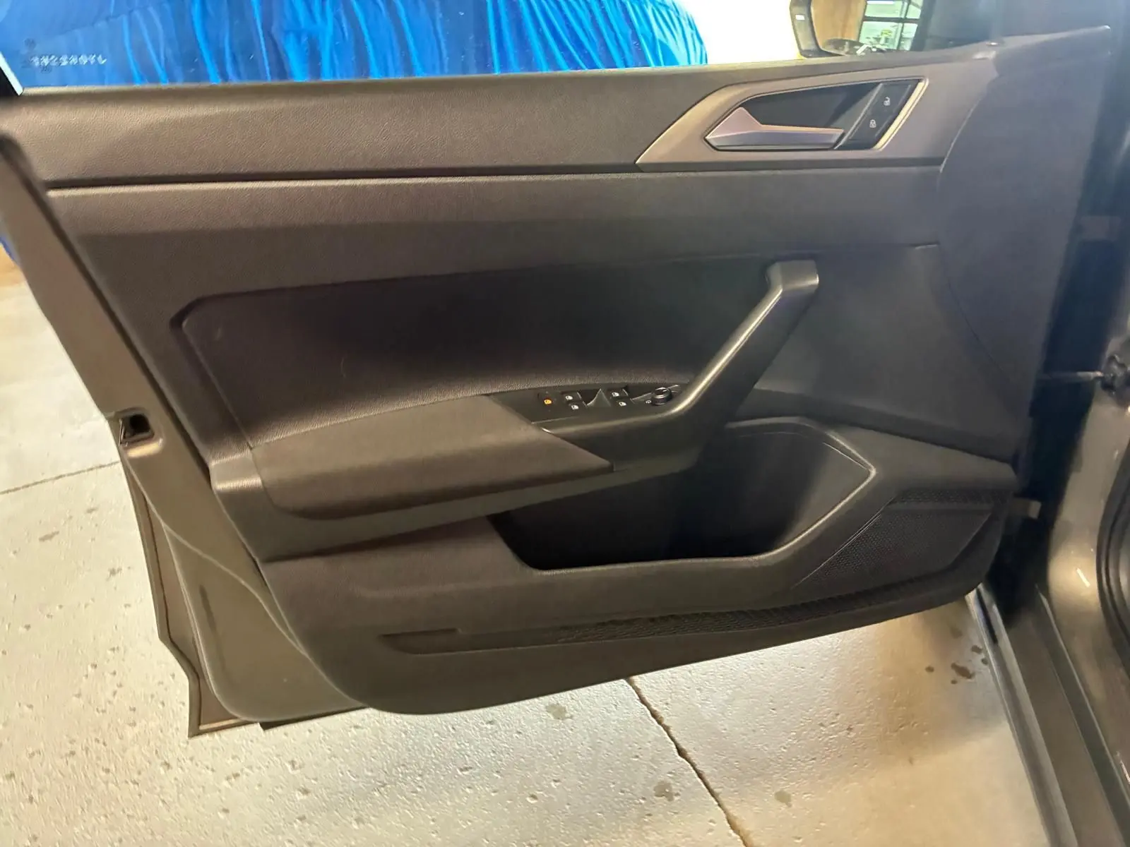 Vue intérieure du panneau de porte avant gauche gris foncé de la Volkswagen Polo 1.0 TSI 95 Confortline 2018 avec commandes électriques.