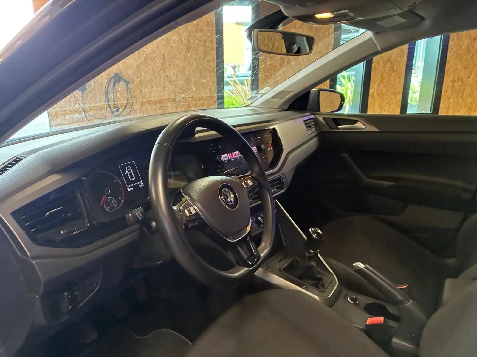 Vue intérieure côté conducteur d'une Volkswagen Polo 1.0 TSI 95 Confortline avec volant noir et boîte manuelle.