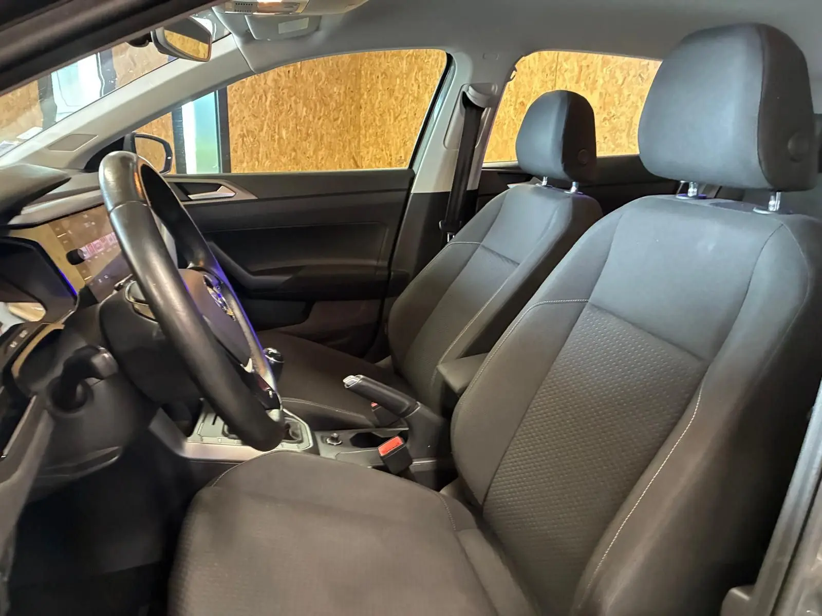 Vue intérieure côté conducteur de la Volkswagen Polo gris 2018, sièges tissu noir et volant multifonction.