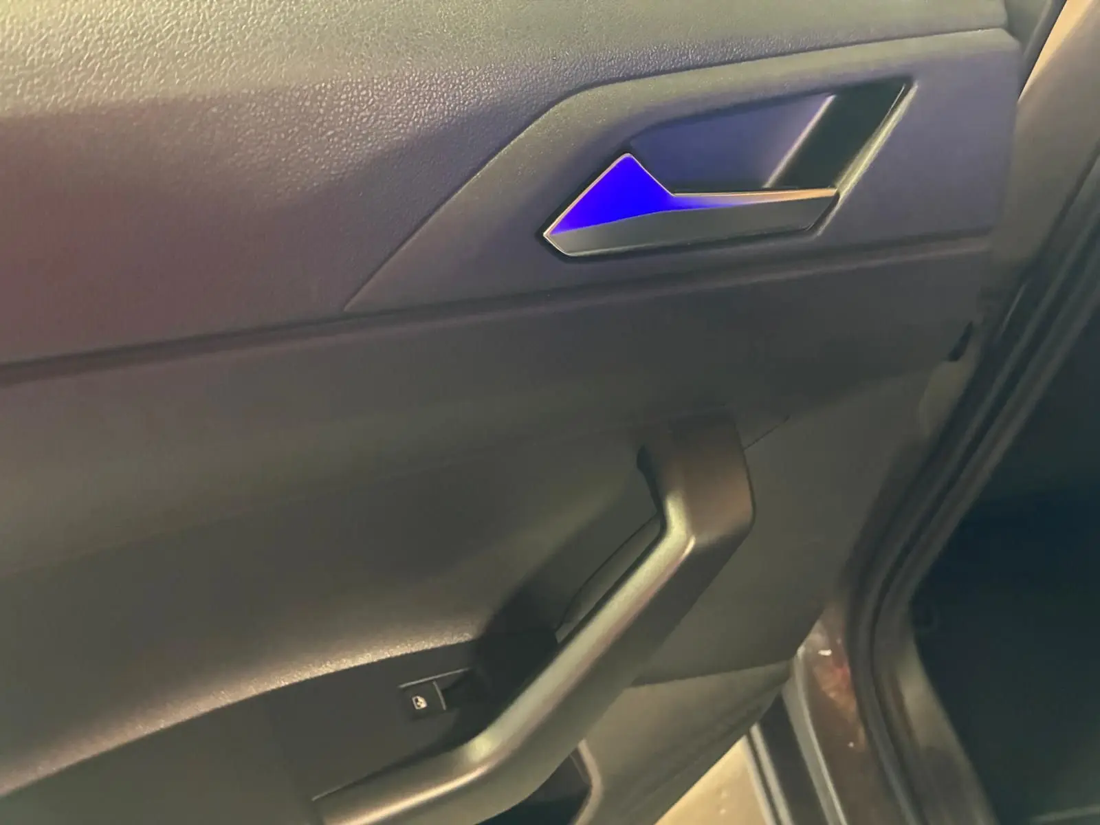 Vue rapprochée de la porte avant gauche de la Volkswagen Polo gris, montrant la poignée intérieure et le bouton de verrouillage.