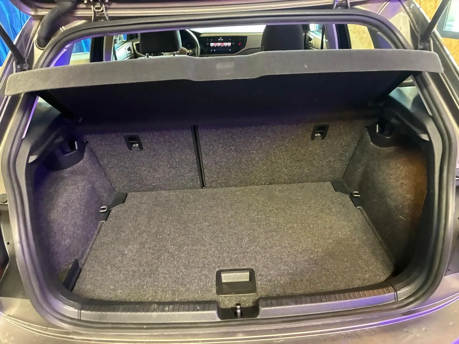 Coffre ouvert vu de l'arrière d'une Volkswagen Polo gris 2018, montrant l'espace de chargement et la tablette arrière relevée.