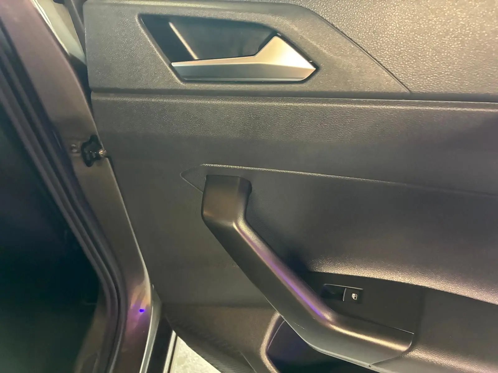 Détail de la porte intérieure côté gauche d’une Volkswagen Polo gris 2018, avec poignée noire et bouton de verrouillage.