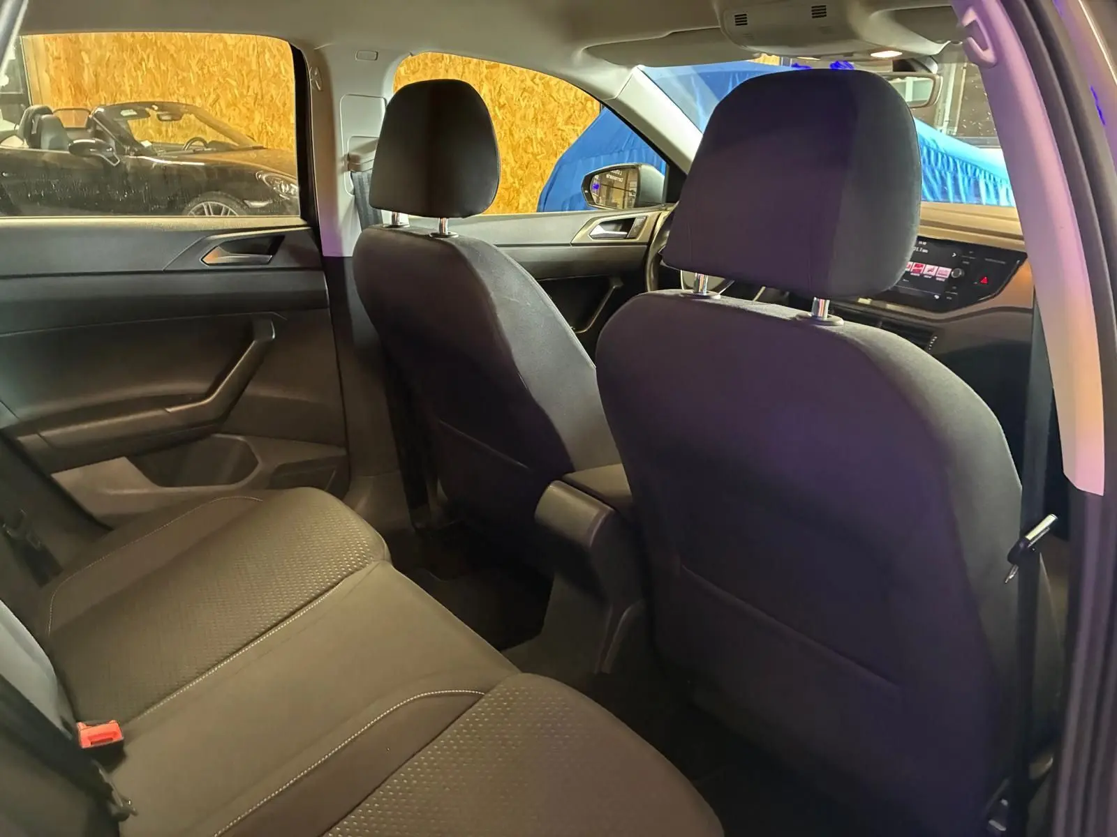 Vue intérieure arrière de la Volkswagen Polo gris 2018, montrant les sièges en tissu noir et le tableau de bord avant.