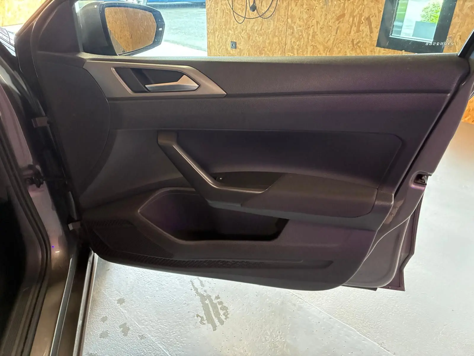 Vue intérieure de la porte avant gauche grise d'une Volkswagen Polo 2018, avec garniture noire et poignée intégrée.