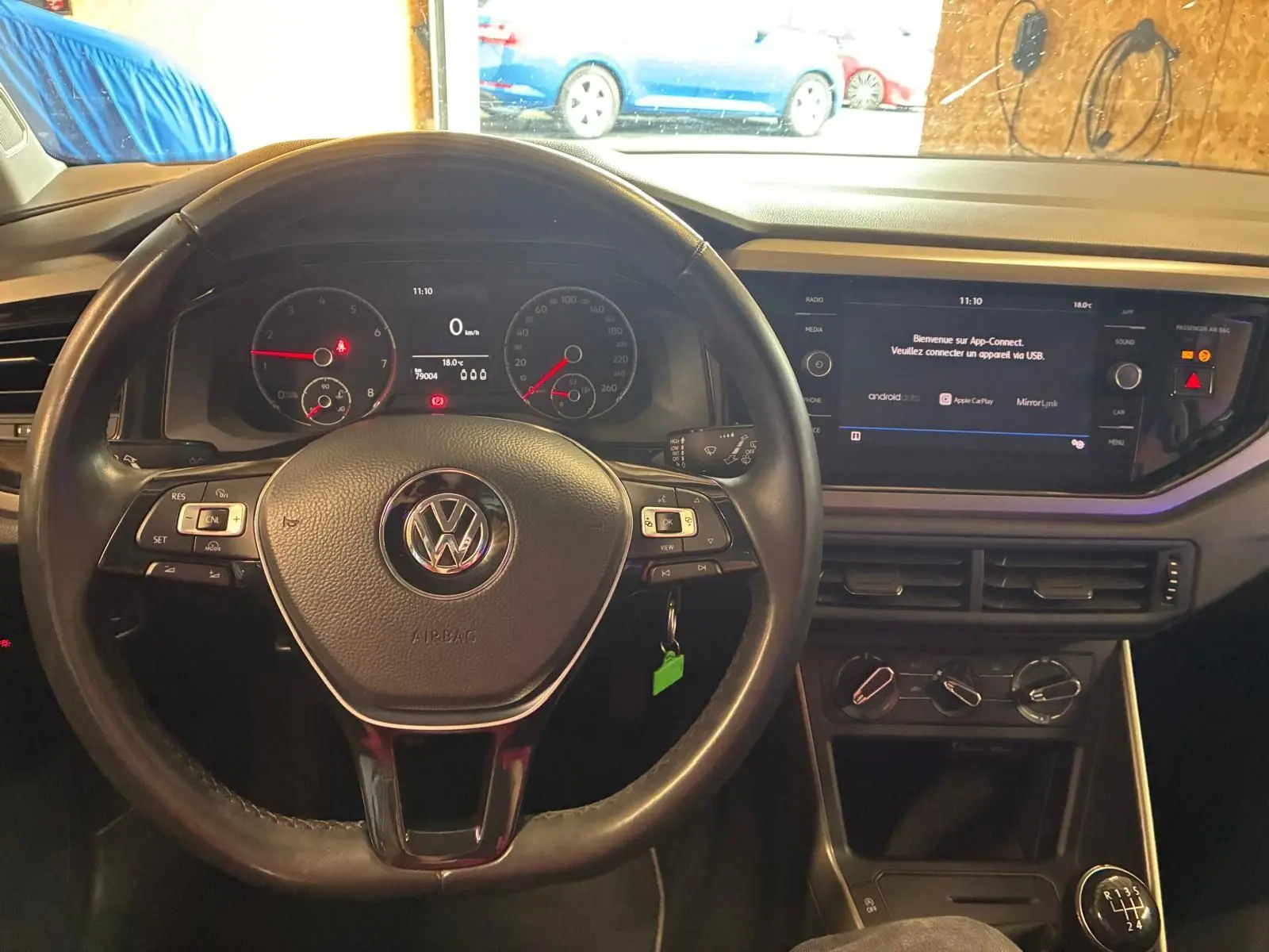 Vue de face de l’intérieur noir d’une Volkswagen Polo 2018, volant multifonctions et écran tactile central allumé.