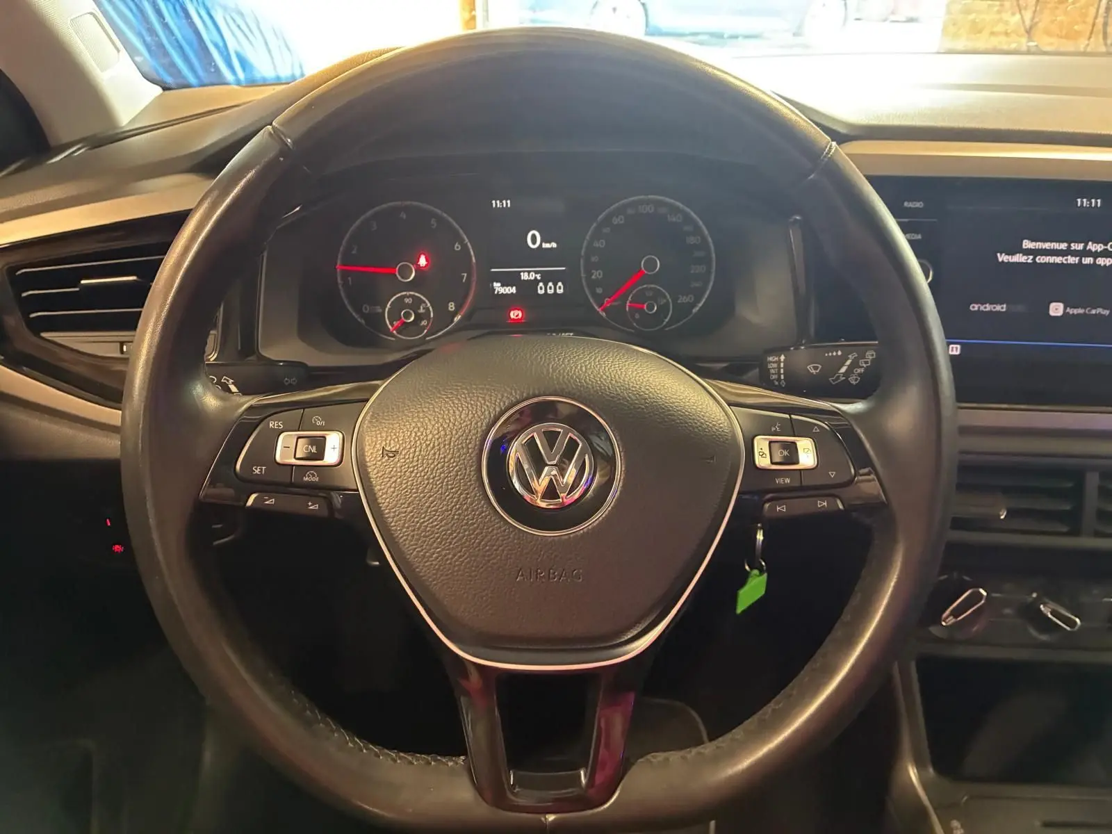 Vue centrée sur le volant noir de la Volkswagen Polo 2018 avec tableau de bord et écran multimédia en arrière-plan.