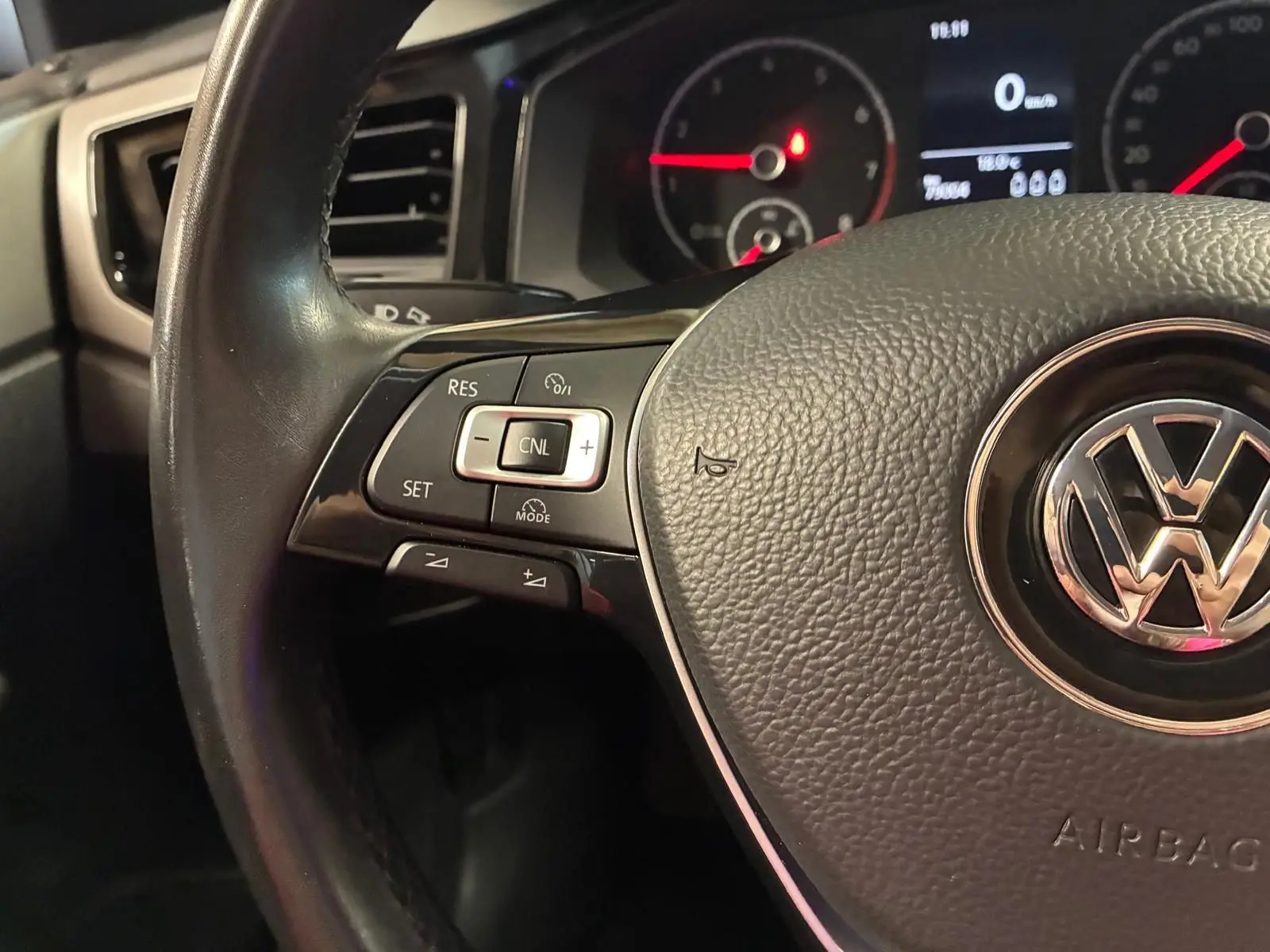 Gros plan sur le volant noir de la Volkswagen Polo 2018 avec commandes intégrées et tableau de bord en arrière-plan.