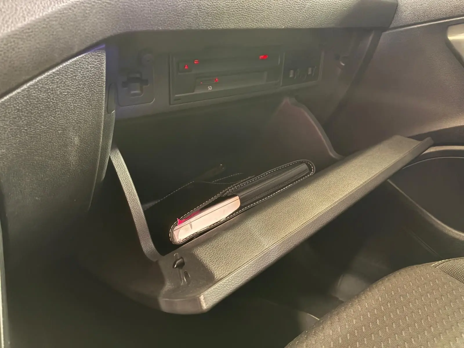 Gros plan de la boîte à gants ouverte de la Volkswagen Polo 1.0 TSI 95 Confortline, intérieur tissu noir.