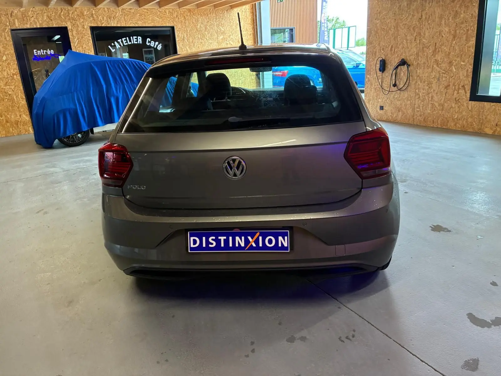 Vue arrière d'une Volkswagen Polo gris métallisé 2018, avec feux arrière rouges et cinq portes, stationnée en intérieur.
