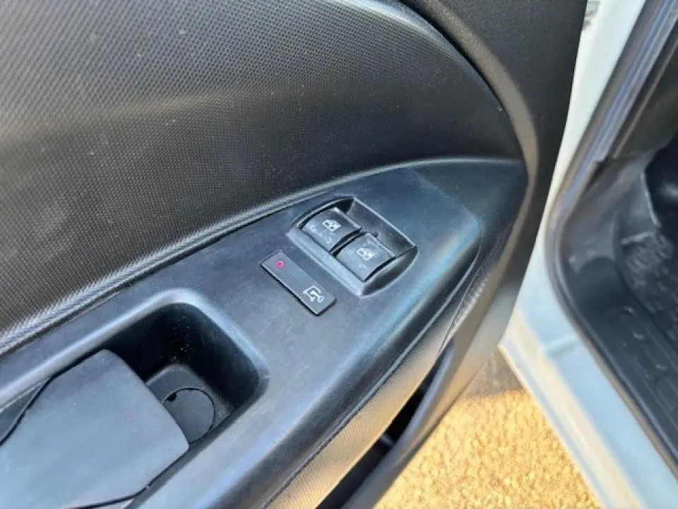 Gros plan sur le panneau de commande des vitres électriques côté conducteur d’un Opel Combo blanc de 2015.