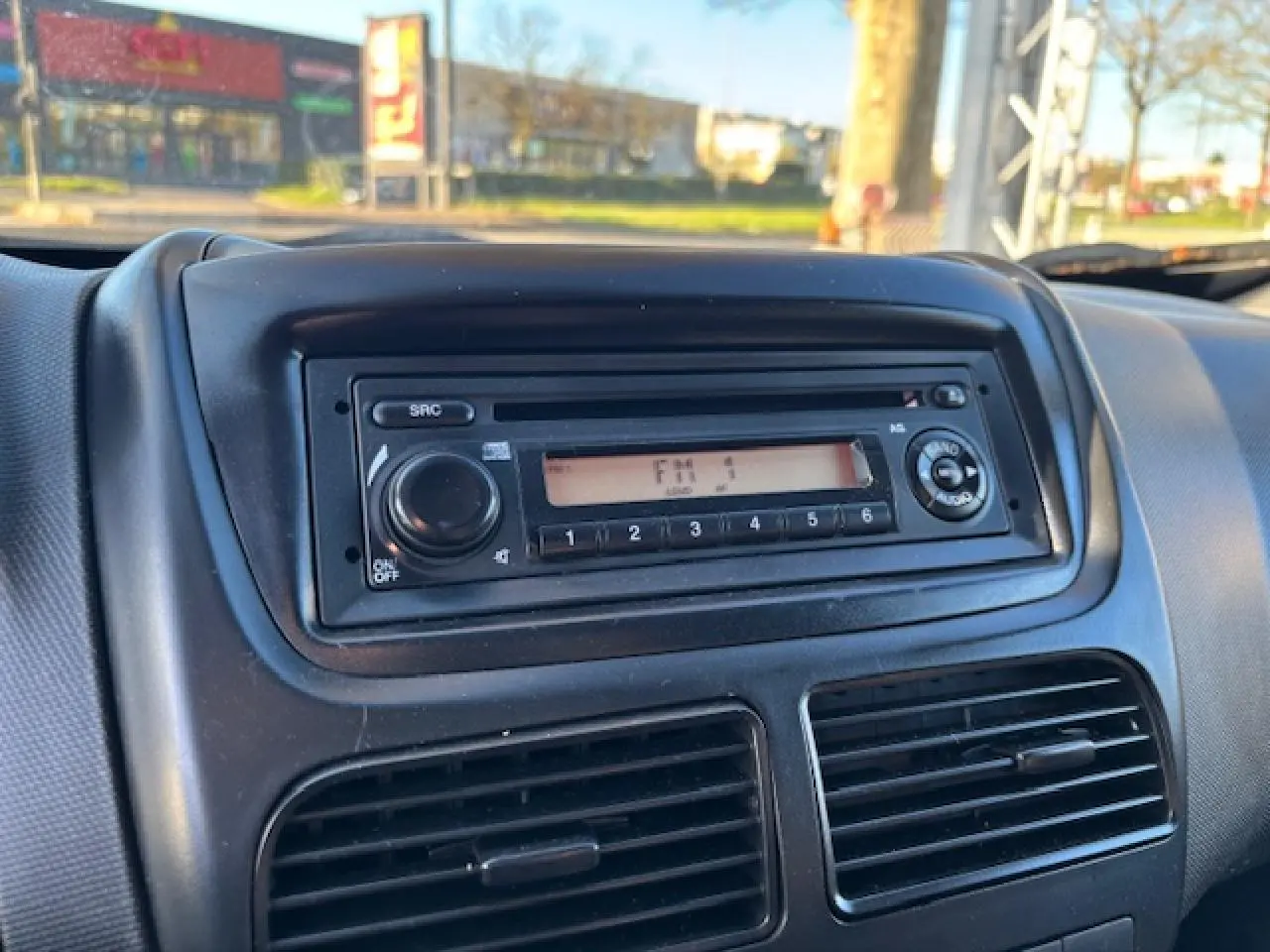 Vue rapprochée de la radio CD noire intégrée au tableau de bord du Opel Combo blanc de 2015.