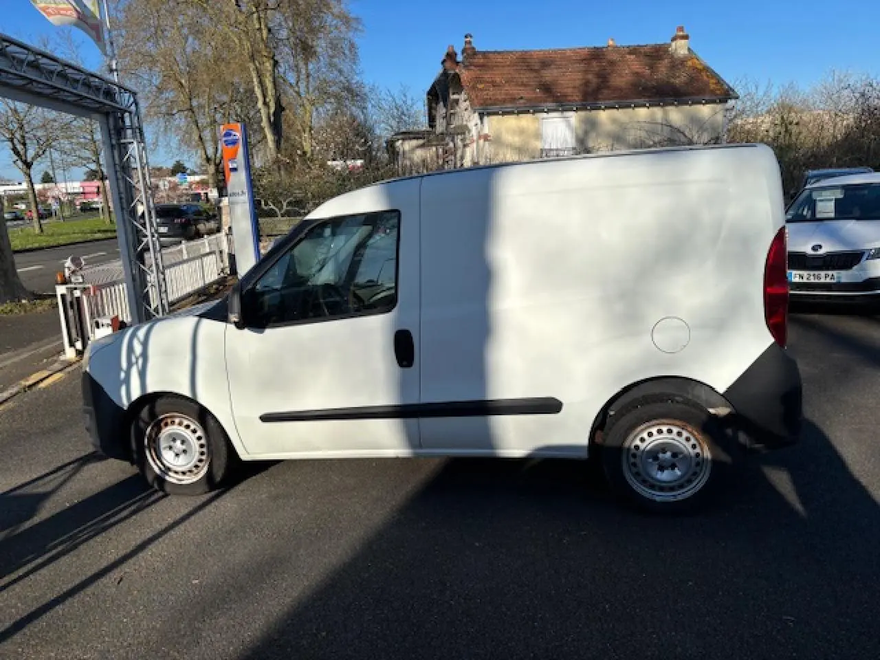 Vue de profil côté gauche d’un Opel Combo blanc avec jantes tôle 15 pouces et porte latérale coulissante tôlée.