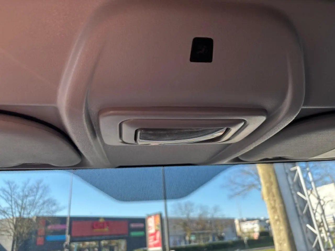 Vue intérieure du plafonnier gris clair de l’Opel Combo blanc, avec pare-brise et paysage urbain en arrière-plan.