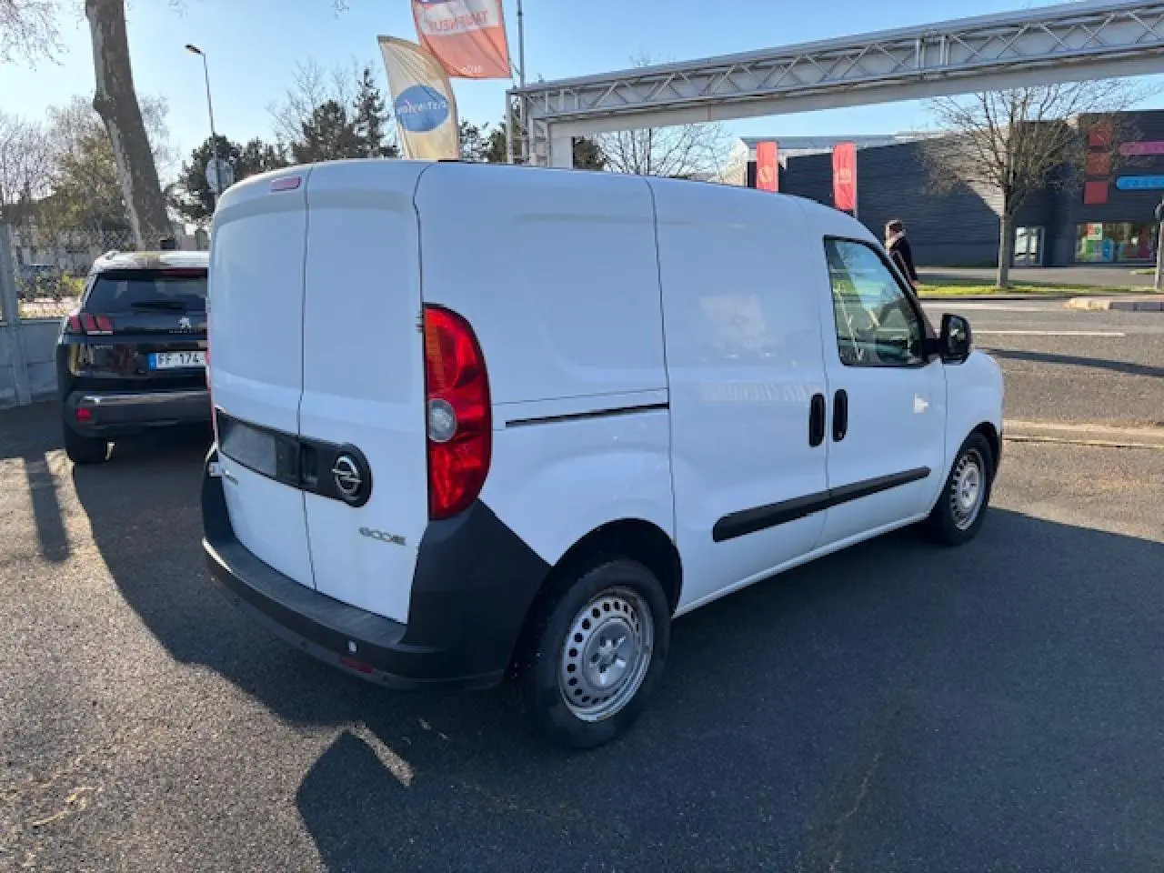 Vue 3/4 arrière droite d'un utilitaire Opel Combo blanc avec porte latérale coulissante et jantes tôle 15 pouces.