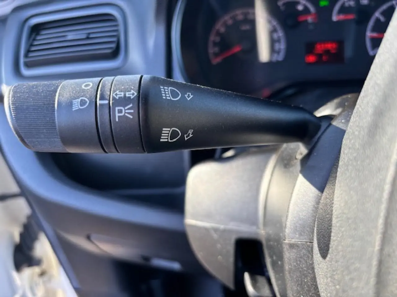 Gros plan sur la manette des feux et clignotants à gauche du volant dans l’habitacle du fourgon blanc Opel Combo L1H1.