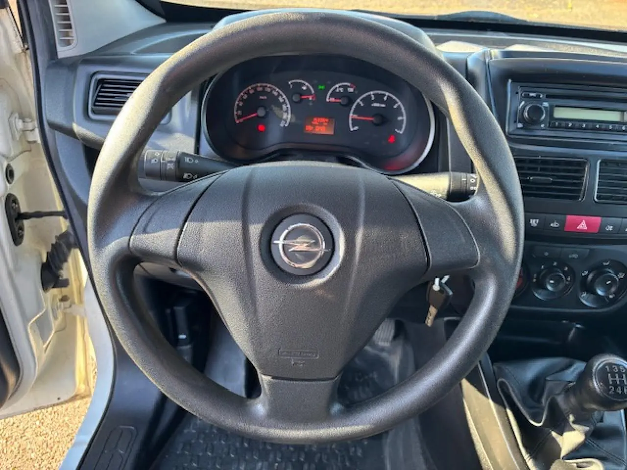 Vue intérieure centrée sur le volant Opel noir, tableau de bord et levier de vitesse d’un Combo blanc de 2015.