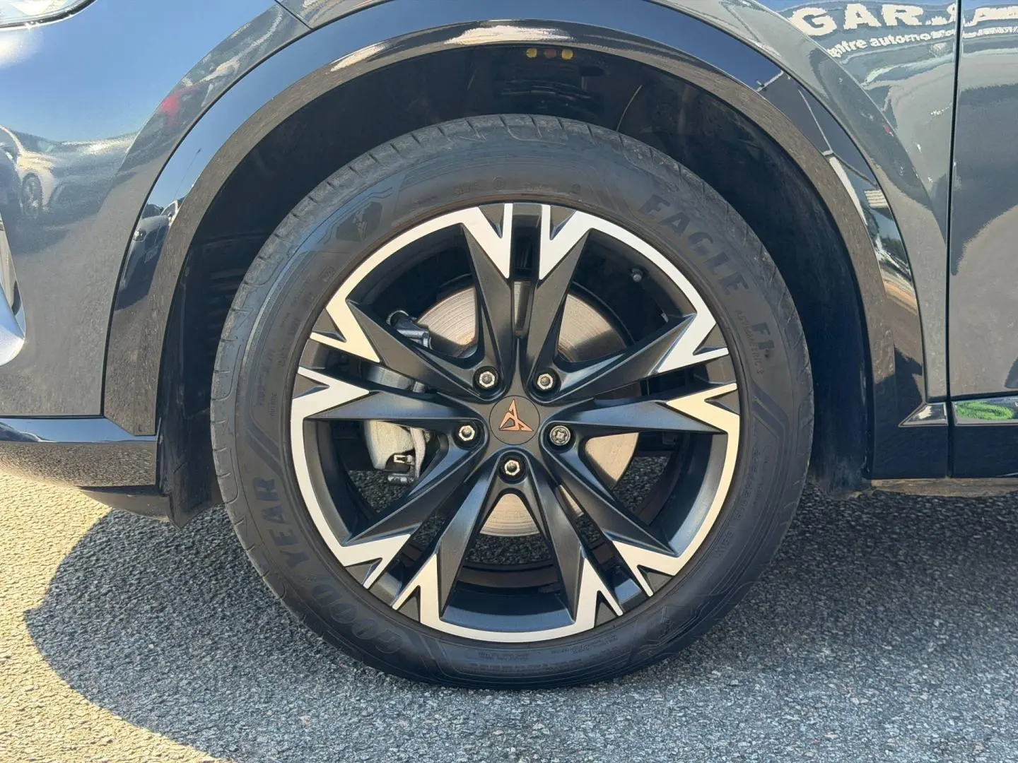 Gros plan sur la jante alu noire et argentée avec logo CUPRA, montée sur un pneu Goodyear, côté avant droit du Formentor gris métallisé.