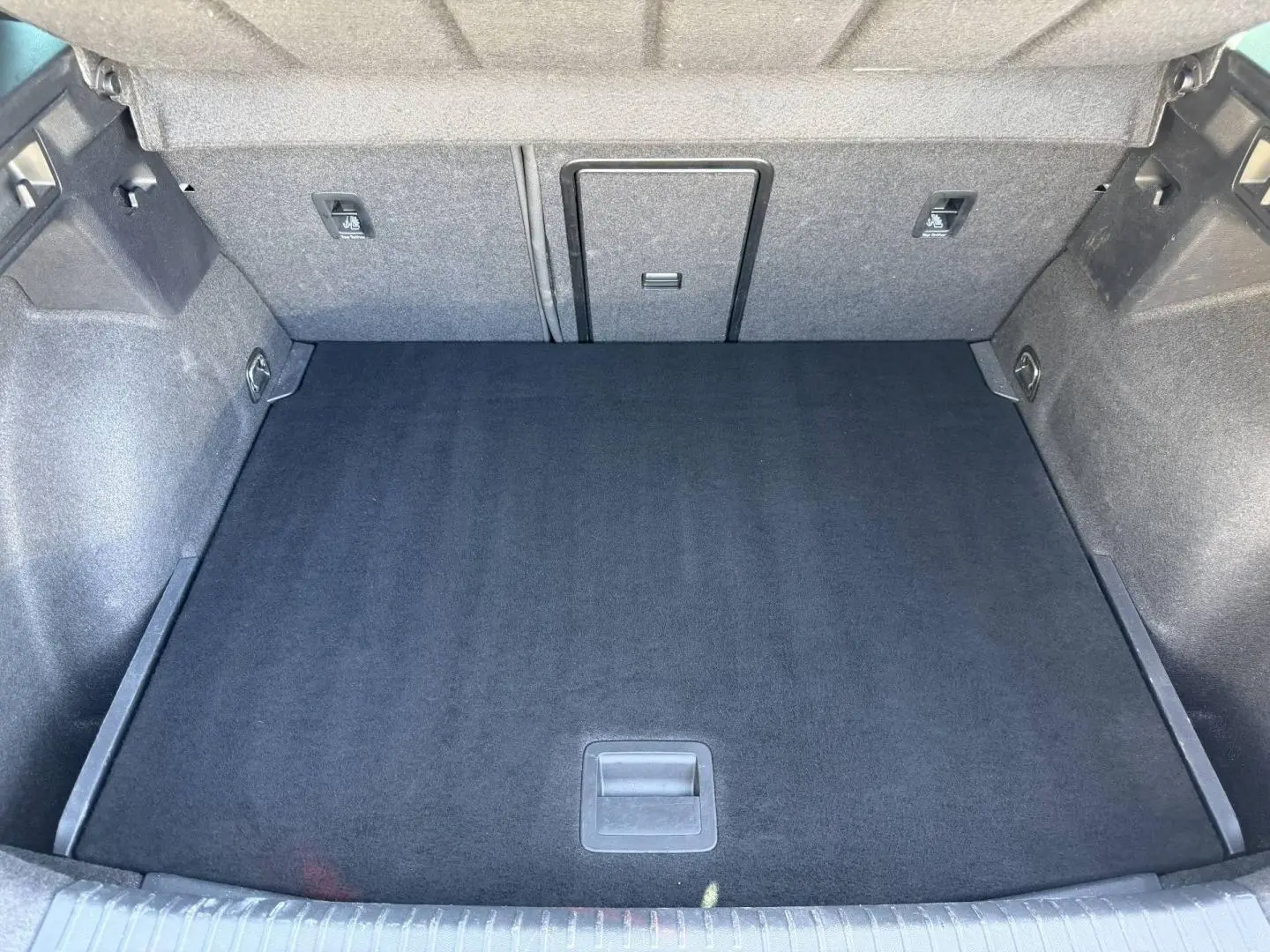 Vue plongeante sur le coffre spacieux et propre du CUPRA Formentor gris magnétique, avec revêtement noir et rangements intégrés.