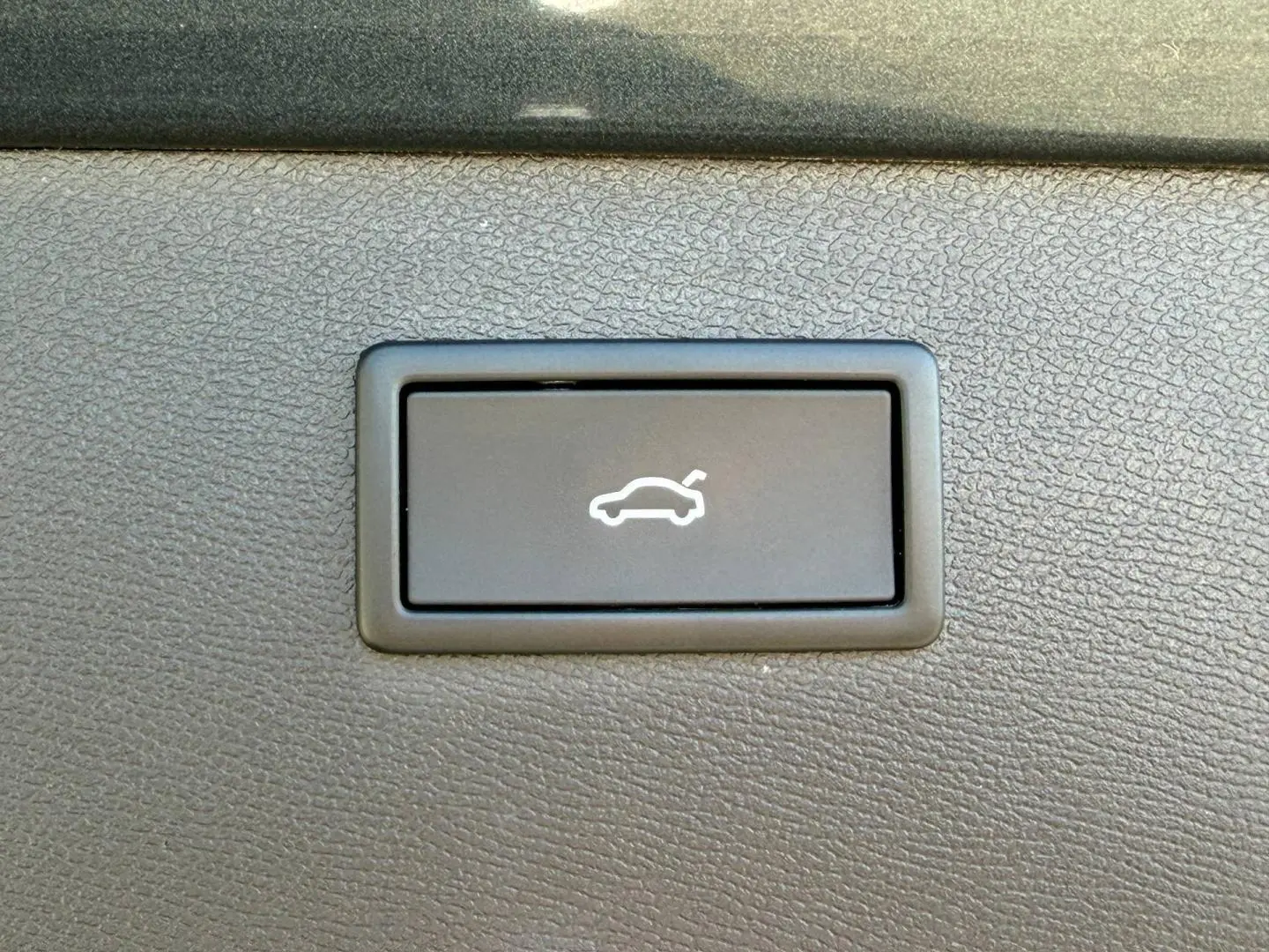 Bouton d'ouverture électrique du coffre sur tableau de bord noir texturé d'un CUPRA Formentor gris métallisé 2025.