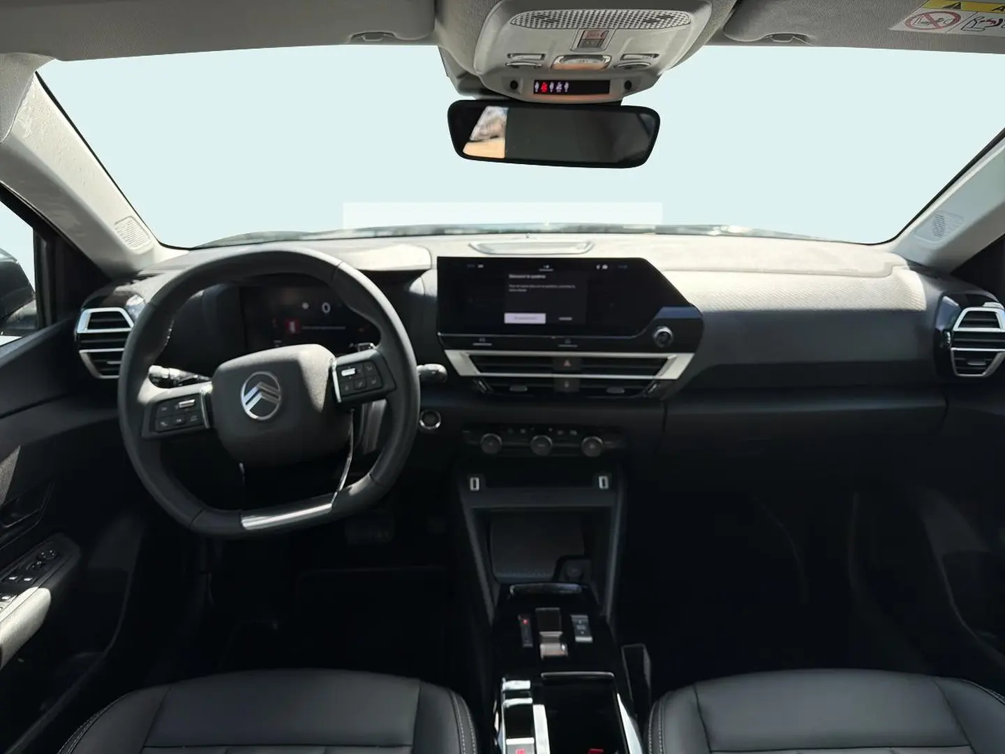Vue intérieure avant du poste de conduite noir de la Citroën C4 X avec écran tactile et volant multifonctions.