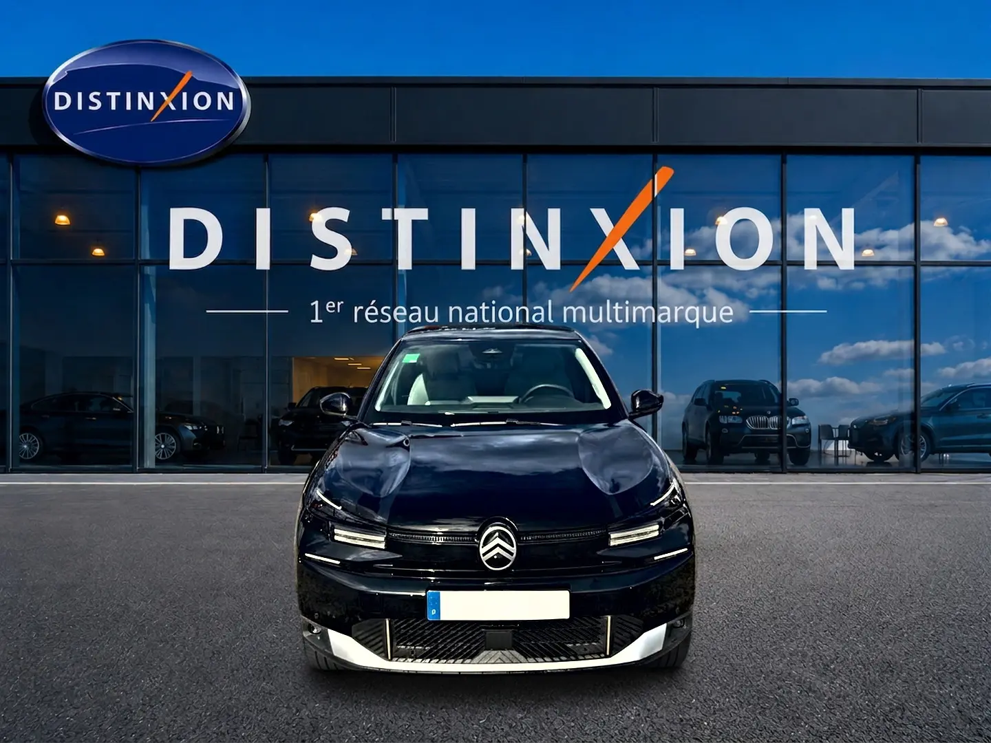 Vue de face d'une Citroën C4 X noire 2025 stationnée devant une vitrine avec logo Distinxion.