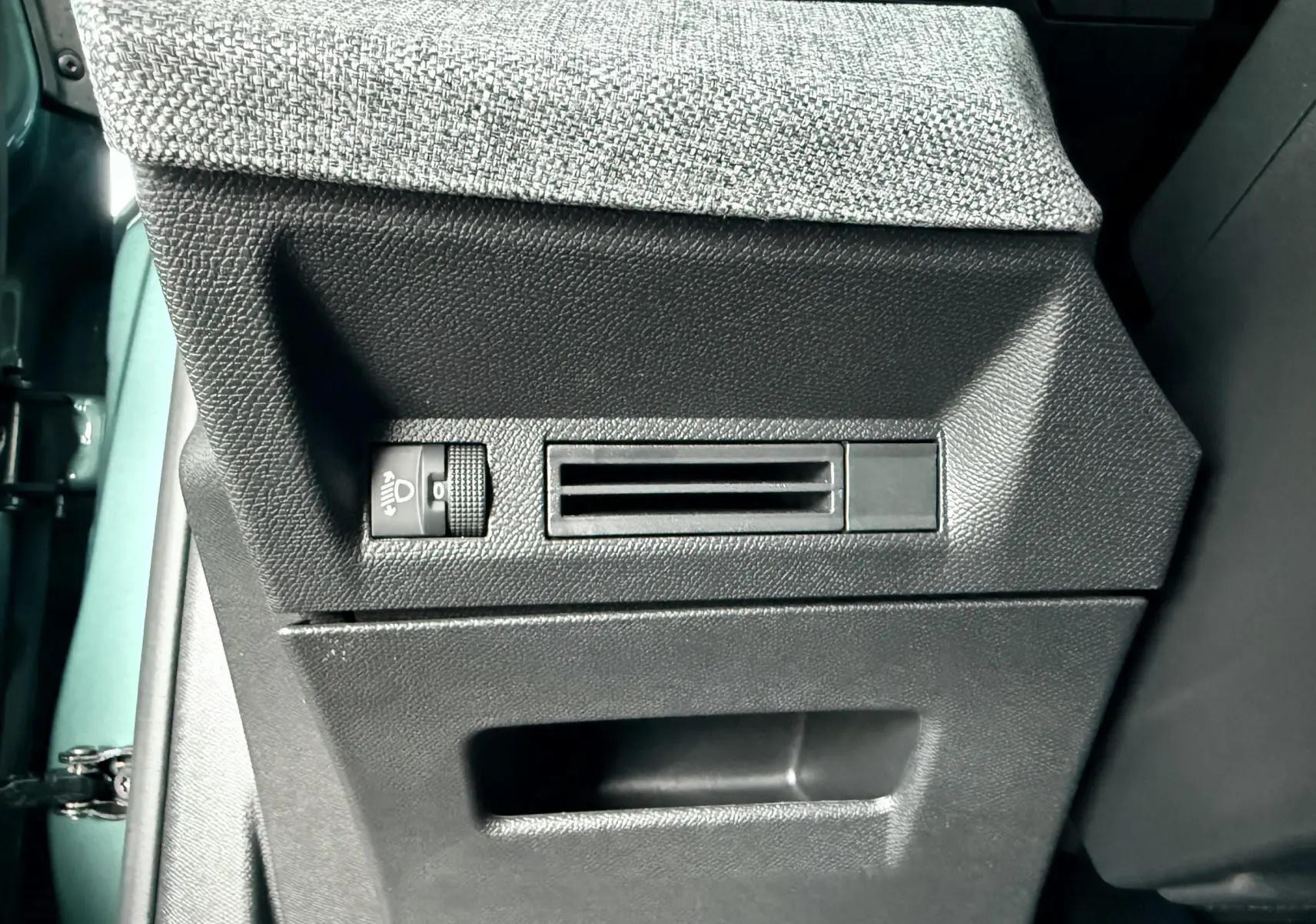 Détail de la console latérale intérieure en tissu gris et plastique noir du Peugeot 3008 Hybrid 2025 bleu Ingaro Metal.