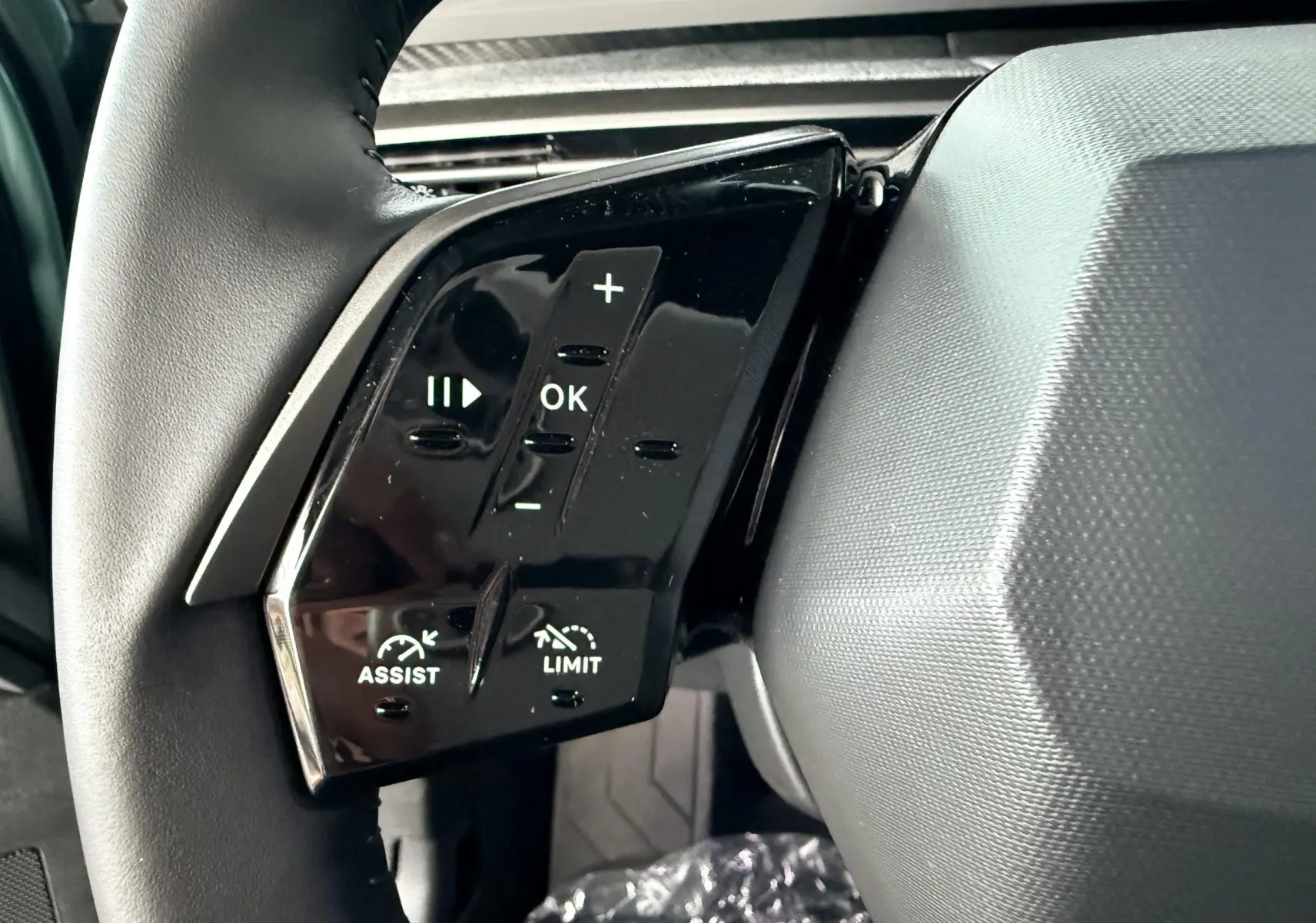 Gros plan sur les commandes au volant gauche du Peugeot 3008 Hybrid 2025 avec boutons de réglage et limitation de vitesse.