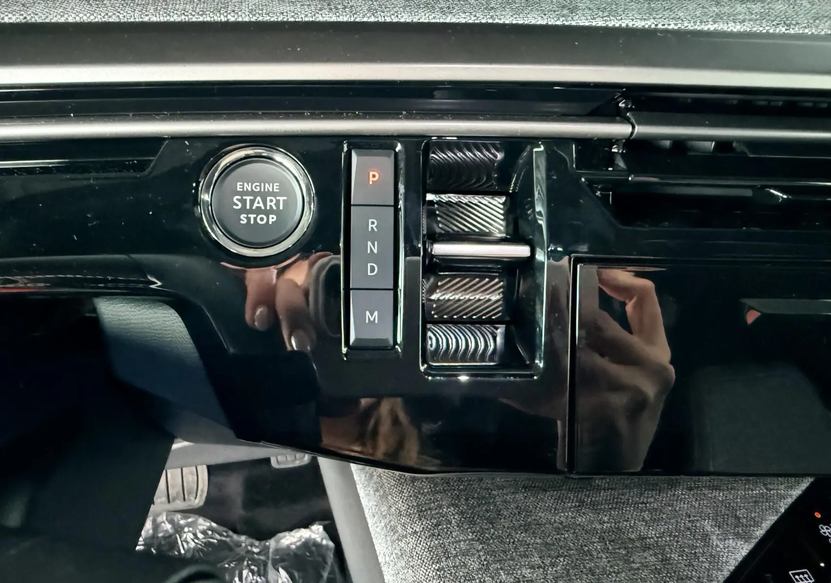 Détail de la console centrale noire brillante du Peugeot 3008 Hybrid 2025 avec bouton start/stop et commandes de boîte automatique.