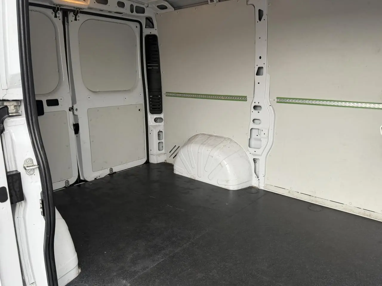 Vue intérieure arrière du fourgon blanc Opel Movano L1H1, montrant le plancher bois et les parois tôlées.