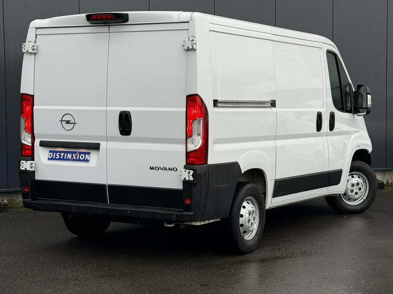 Vue 3/4 arrière droite d’un fourgon Opel Movano blanc avec portes arrière battantes et bandeau noir inférieur.