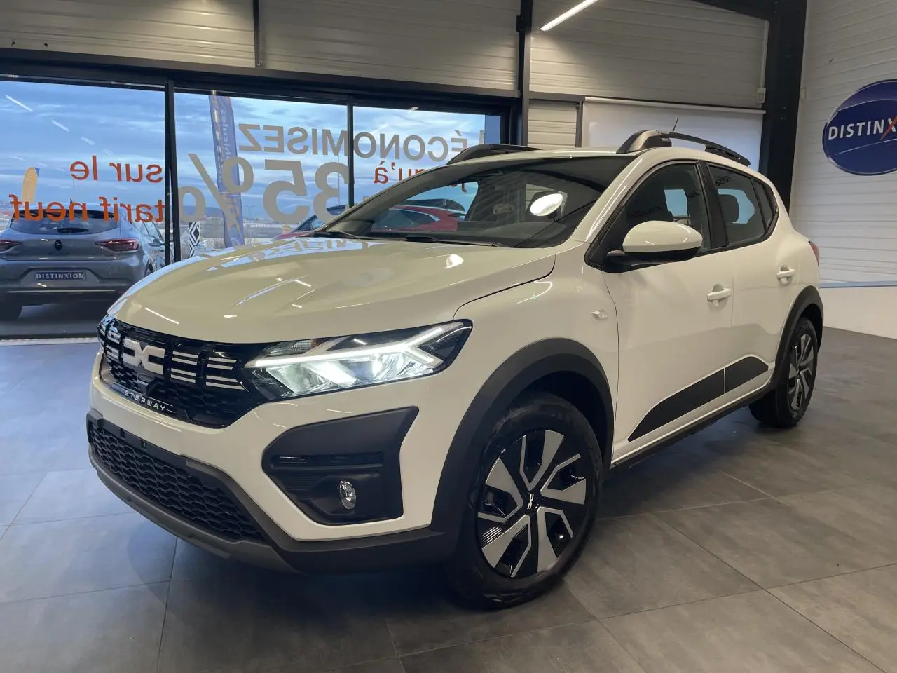 Vue 3/4 avant droite d'une Dacia Sandero Stepway 2025 blanc glacier avec calandre noire et jantes spécifiques Stepway.