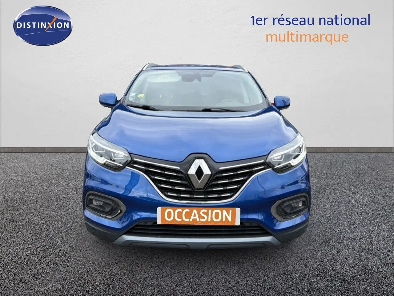 Vue avant d'un Renault Kadjar bleu Iron 2021 avec calandre chromée et phares LED allumés.