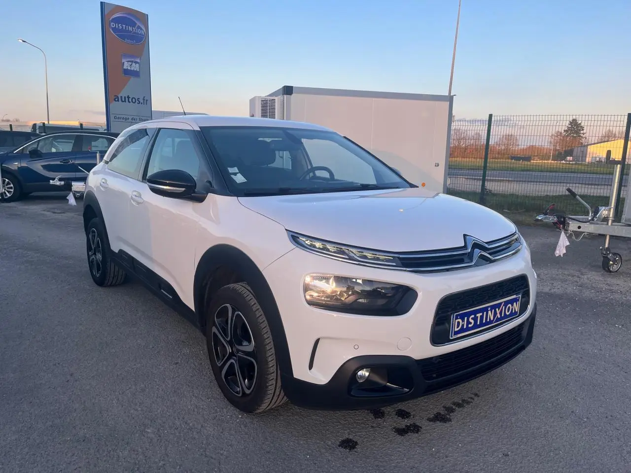 Citroën C4 Cactus blanc vue 3/4 avant droit, avec protections noires et jantes alliage distinctives.