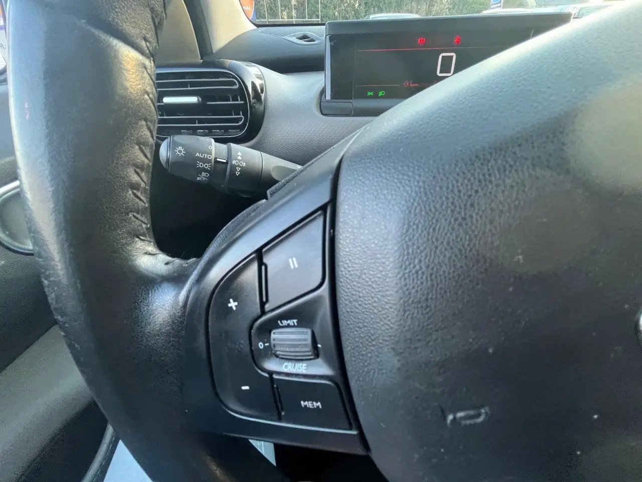 Gros plan sur le volant noir de la Citroën C4 Cactus 2020 avec commandes intégrées et tableau de bord digital en arrière-plan.