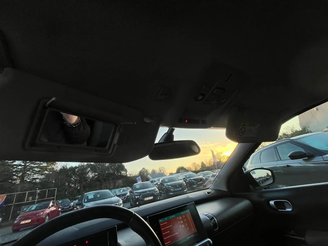 Vue intérieure du poste de conduite du Citroën C4 Cactus 2020, avec tableau de bord et écran tactile visible au coucher du soleil.