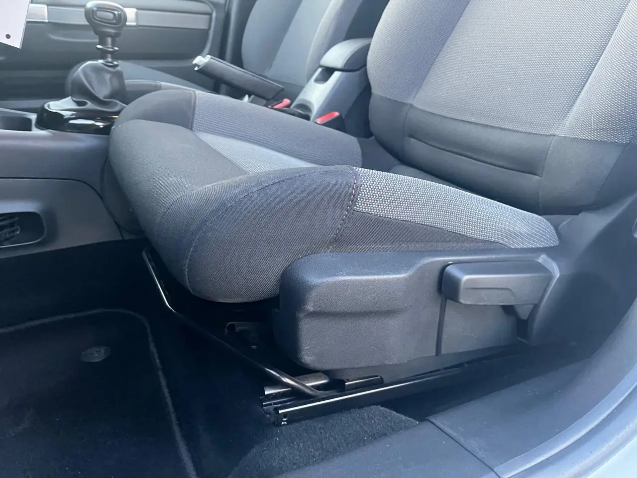 Gros plan sur le siège avant gauche et levier de vitesse manuel d'une Citroën C4 Cactus 2020 blanche, intérieur tissu gris.