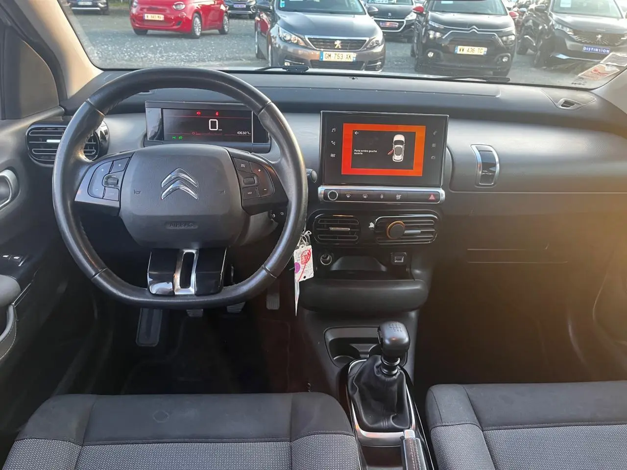 Vue intérieure avant du Citroën C4 Cactus 2020 diesel blanc, volant multifonction et écran tactile central allumé.