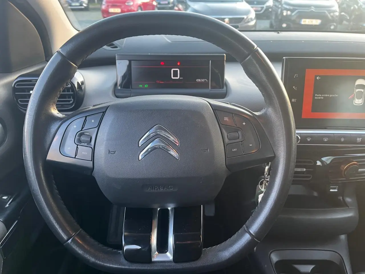 Vue rapprochée du volant noir de la Citroën C4 Cactus 2020 avec tableau de bord digital et écran tactile central allumé.