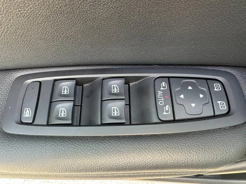 Panneau de commandes des vitres et rétroviseurs sur porte intérieure noire d'une Renault Mégane Break gris Titanium 2024.