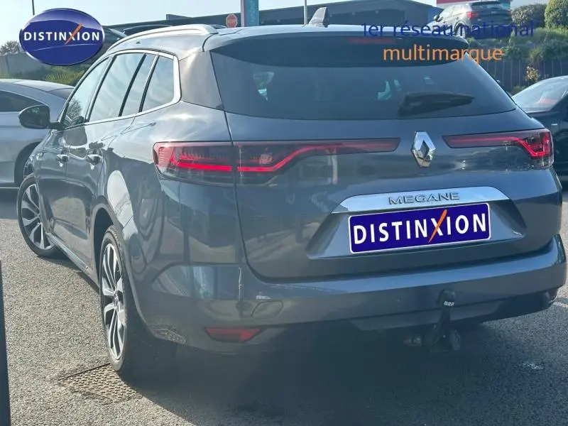 Renault Mégane Break gris titanium vue 3/4 arrière droit avec feux arrière LED et attelage visible.