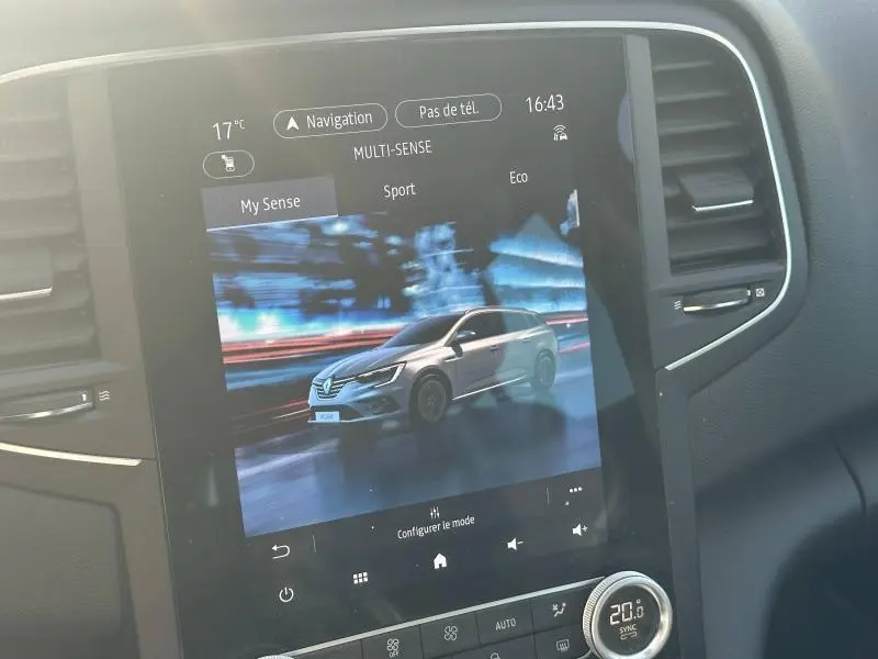 Écran tactile intérieur montrant une Renault Mégane Break gris titanium en vue 3/4 avant dynamique.