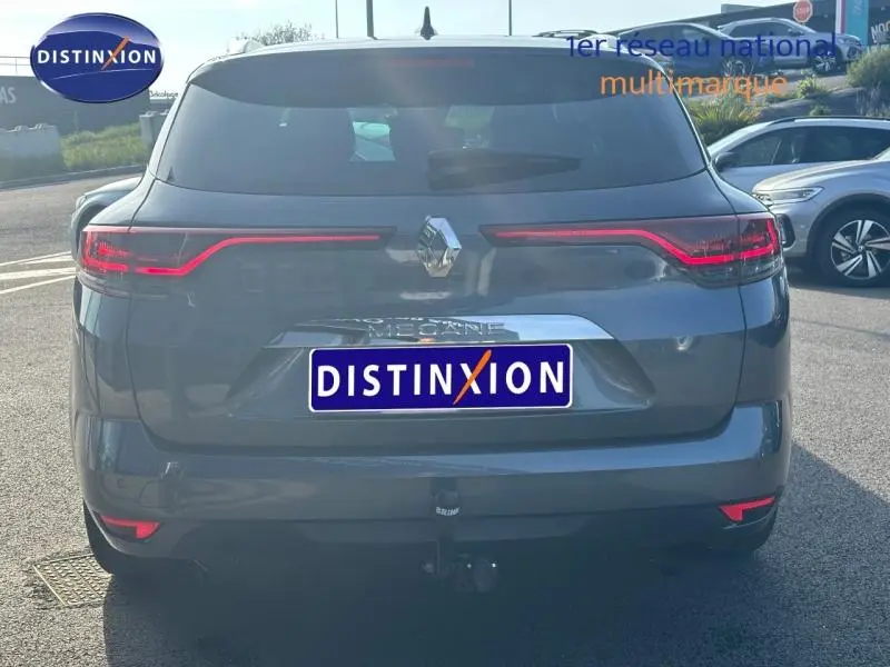 Vue arrière d'une Renault Mégane Break gris titanium 2024 avec feux LED et attelage visible en extérieur.