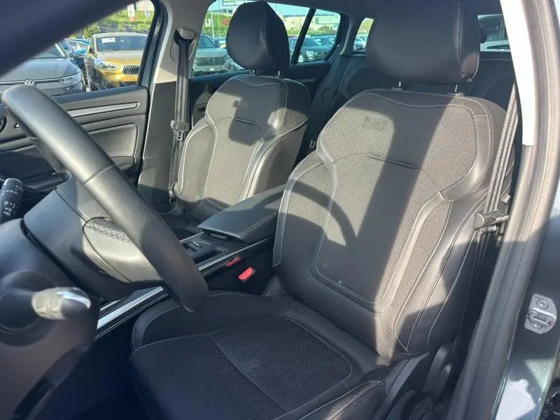 Vue intérieure côté conducteur de la Renault Mégane Break 2024, sièges noirs en tissu et similicuir avec surpiqûres blanches.