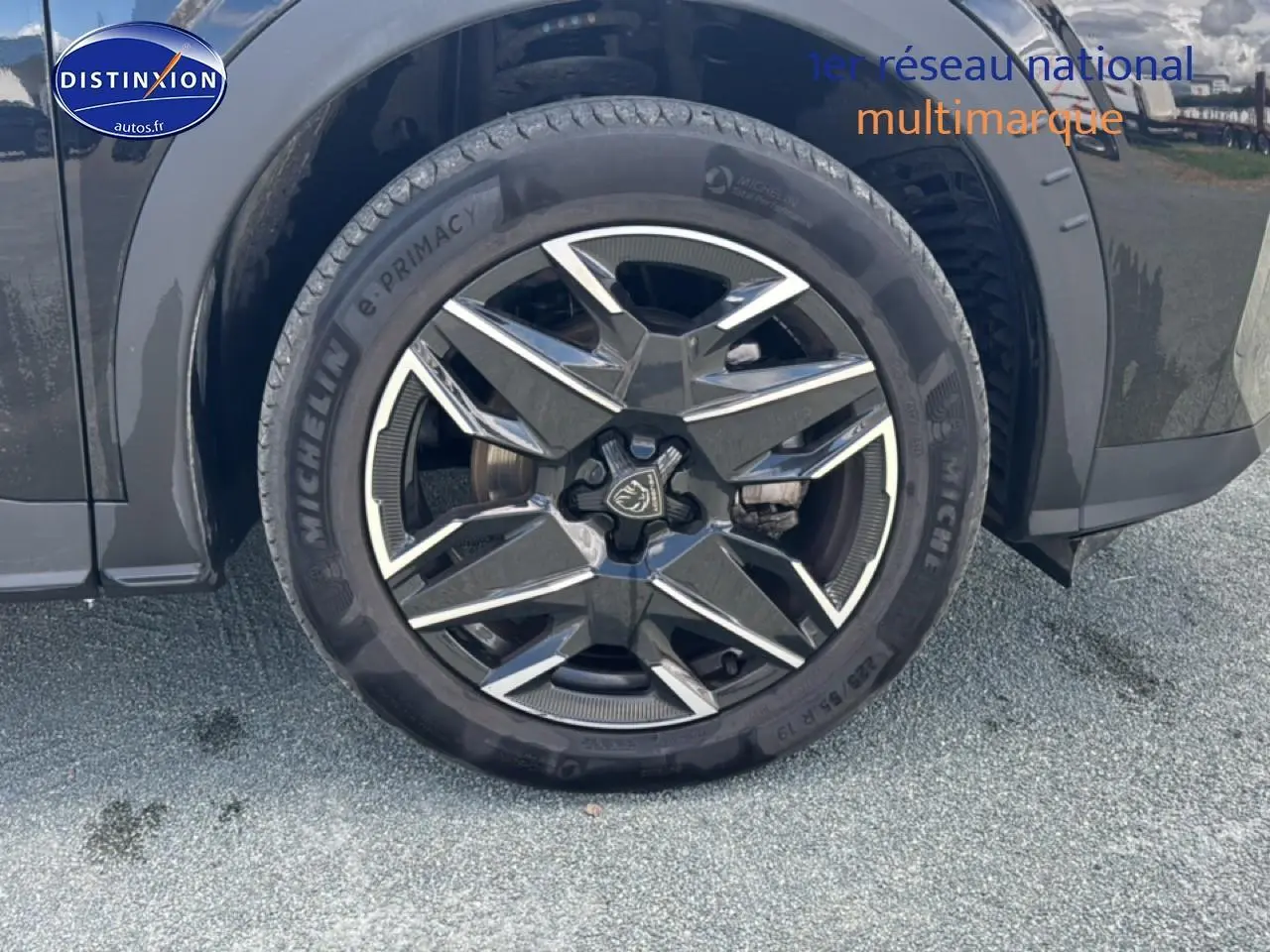 Gros plan sur la roue avant gauche noire du Peugeot 5008 Hybrid 145 allure e-dcs6 avec jante alu distinctive.