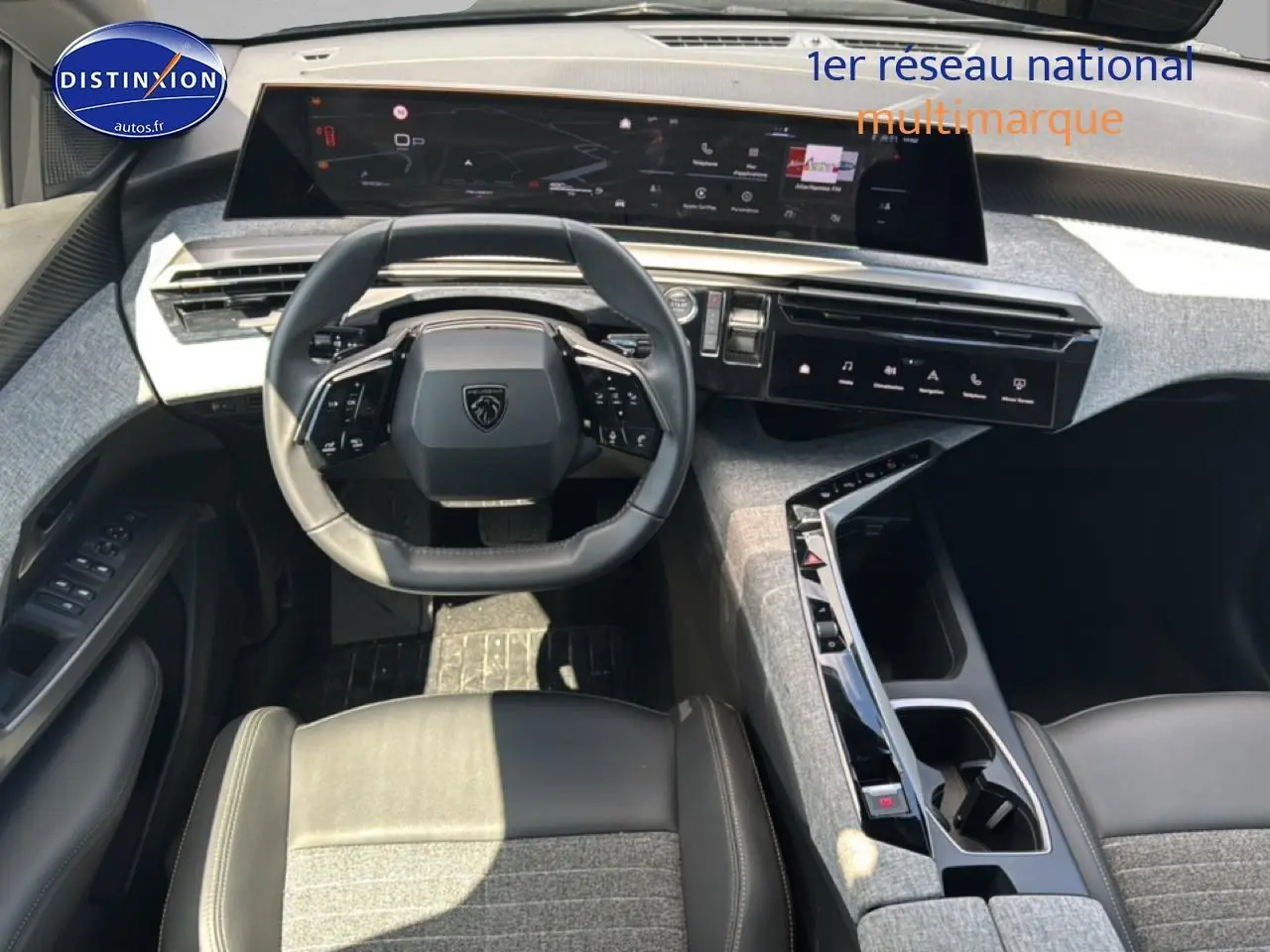 Vue intérieure du poste de conduite du Peugeot 5008 Hybrid 145 allure e-dcs6 2025 avec volant cuir et écran tactile panoramique.