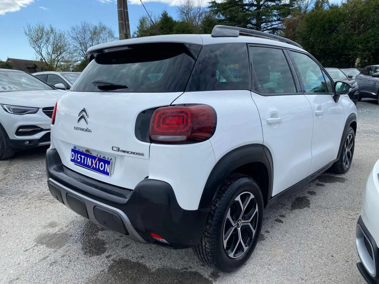 Vue 3/4 arrière droite d'un Citroën C3 Aircross blanc 2023 avec toit noir et jantes alliage distinctives.