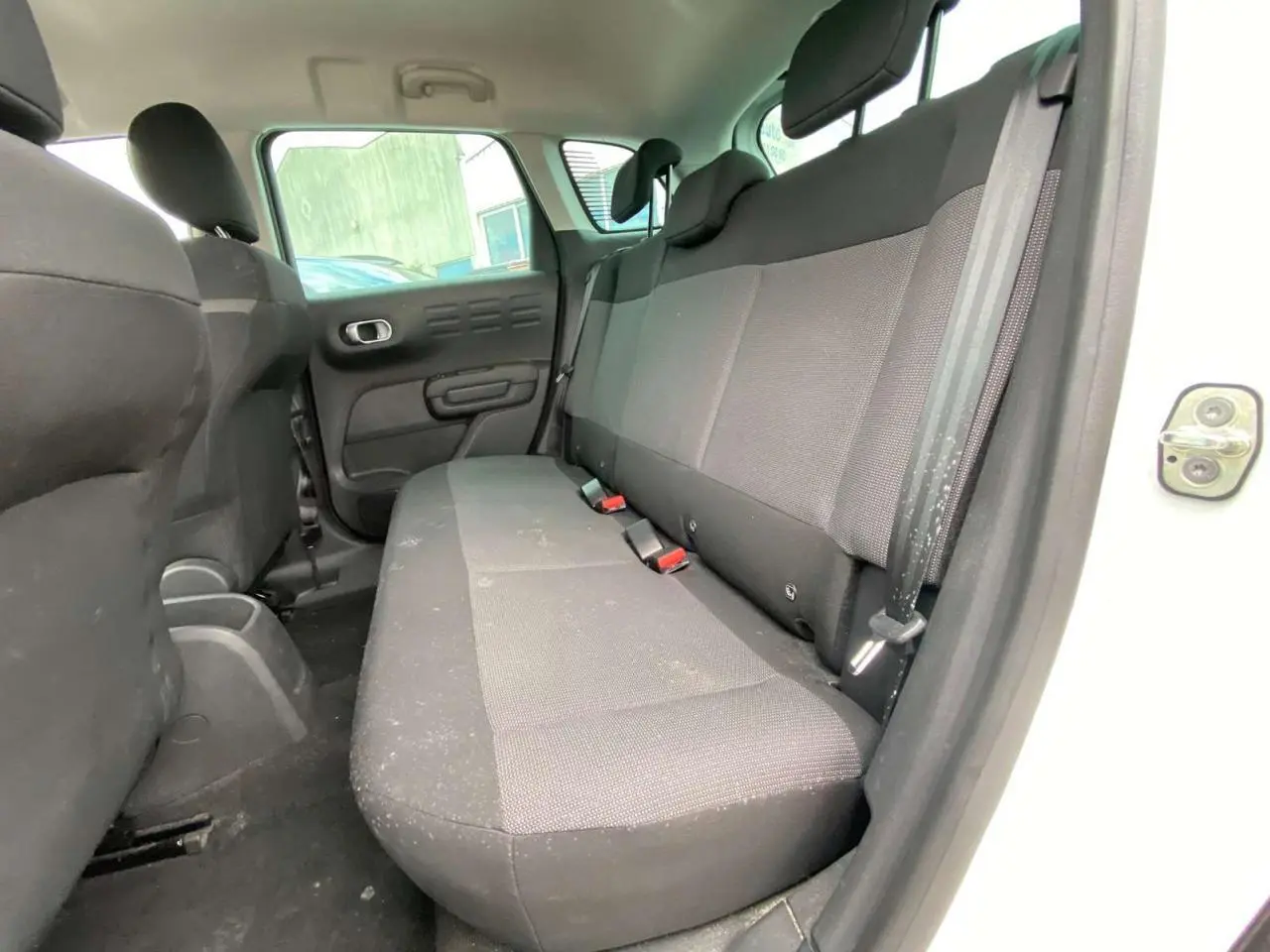 Vue intérieure côté droit sur la banquette arrière noire du Citroën C3 Aircross blanc, porte arrière ouverte.