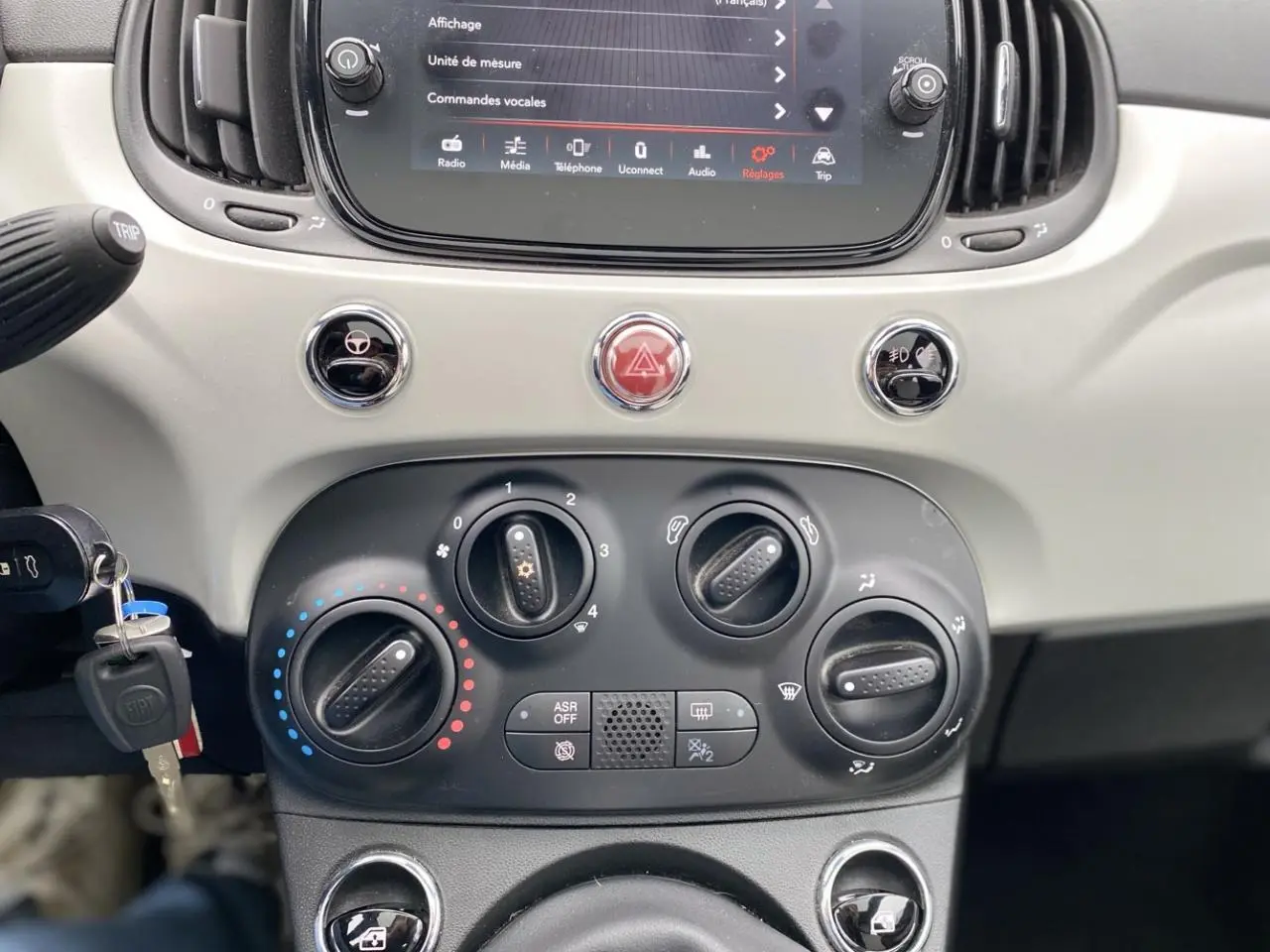Vue rapprochée du tableau de bord beige clair de la Fiat 500 2019 avec commandes climatisation et écran tactile.
