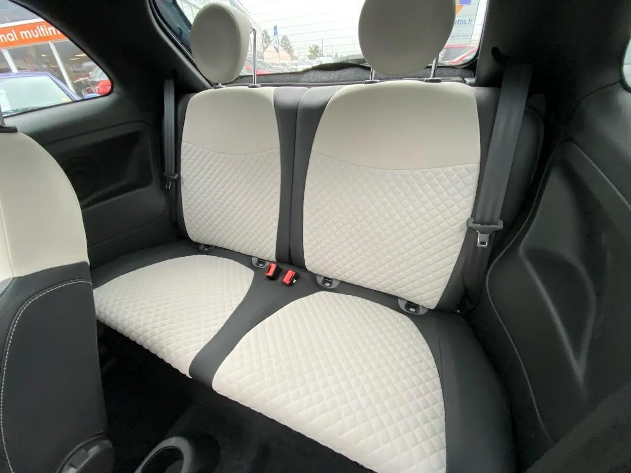 Vue intérieure sur les sièges arrière bi-ton crème et noir de la Fiat 500 2019 avec toit panoramique.